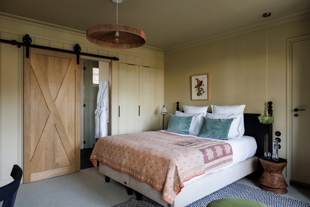 Chambre deluxe terrasse mer et sa salle de bain, ses tableaux, son lit et son bureau de bois dans notre hôtel de luxe en bretagne