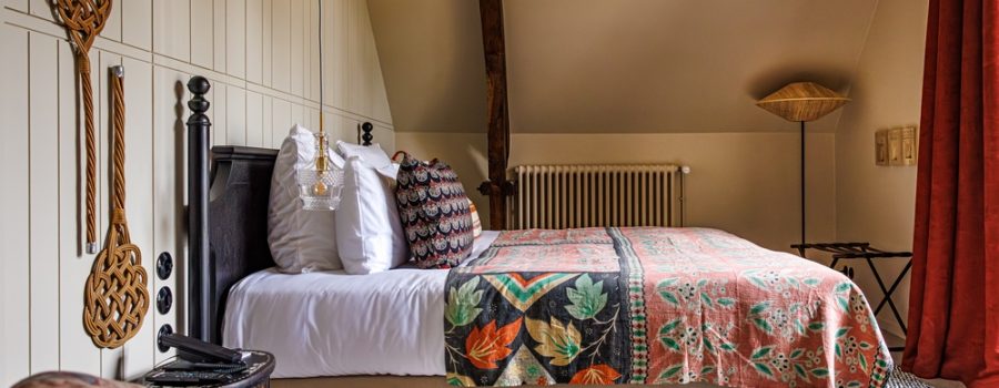 Chambre rustique avec lit orné, décoration en bois, et touches de couleur dans la chambre cosy parc de notre hotel de luxe relais et chateau morbihan en bretagne